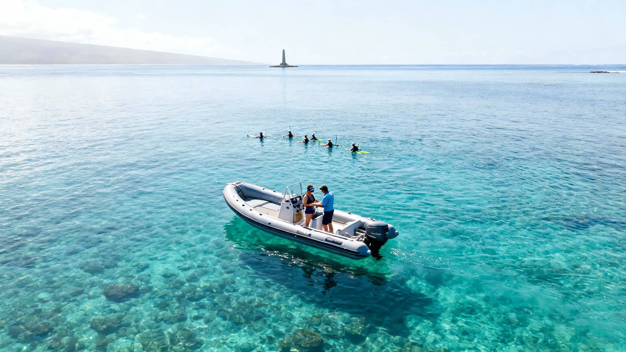 Aerial view of a boat with two people in clear blue water, with paddleboarders and a distant lighthouse.